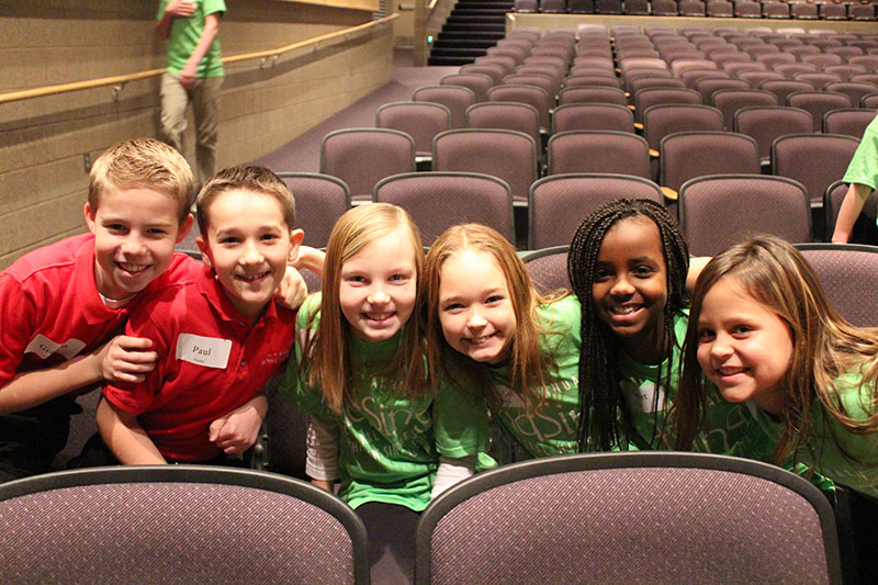 Boy and girl campers smiling together in an auditorium